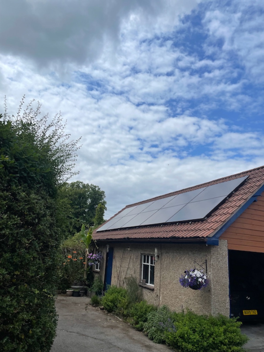 An all-black solar array on a Bristol roof, blue sky behind